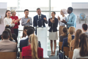 people standing at podium clapping at corporate event