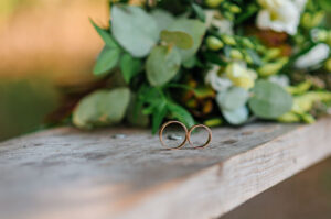 Wedding rings on a wooden stand against the background of the bride's bouquet