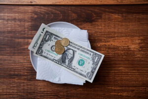 Restaurant tips or gratuity. Banknotes and coins on a plate.