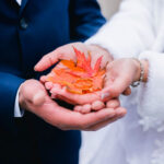 Wedding rings on orange autumn leaves in hands of wedding couple. Wedding concept.